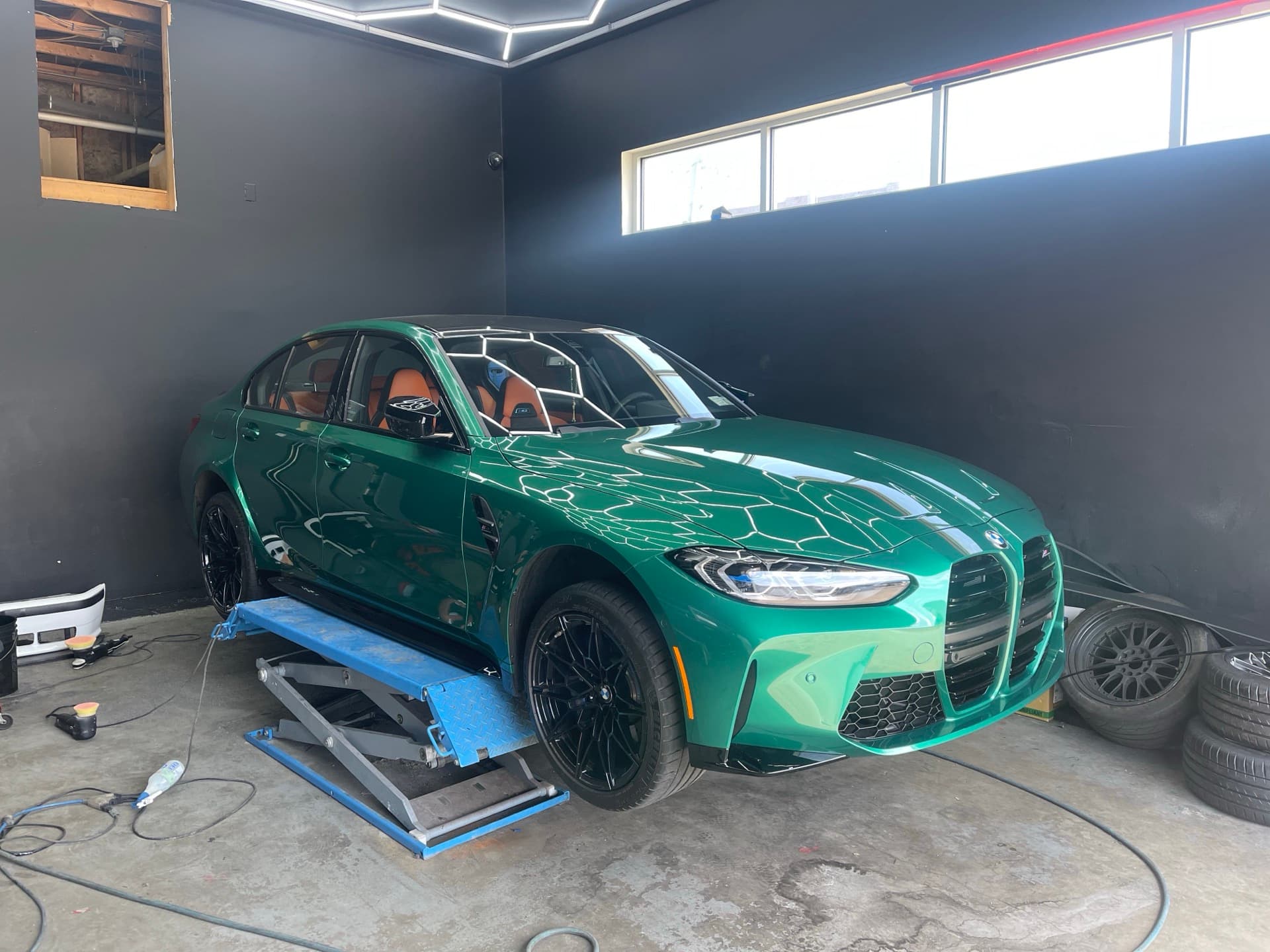 Green BMW M3 on lift in detailing bay