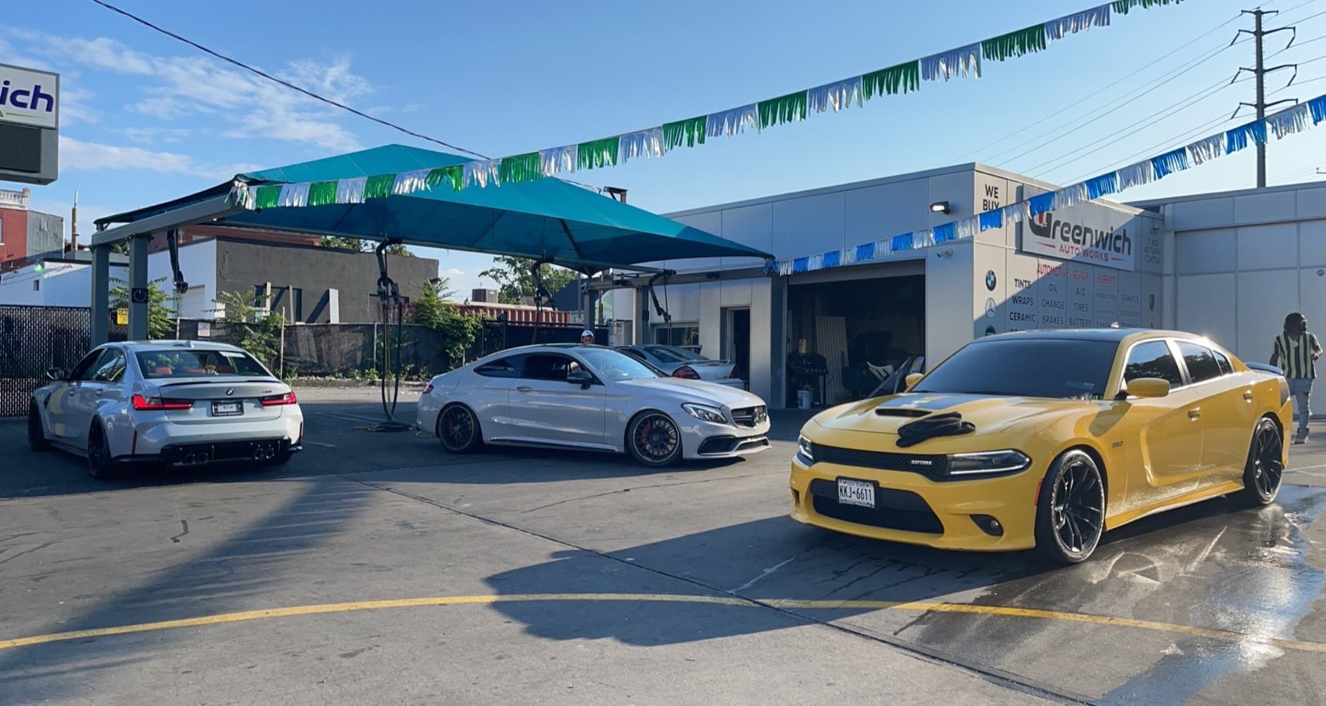 Facility exterior with BMW, Mercedes C63 AMG, and yellow Dodge Charger