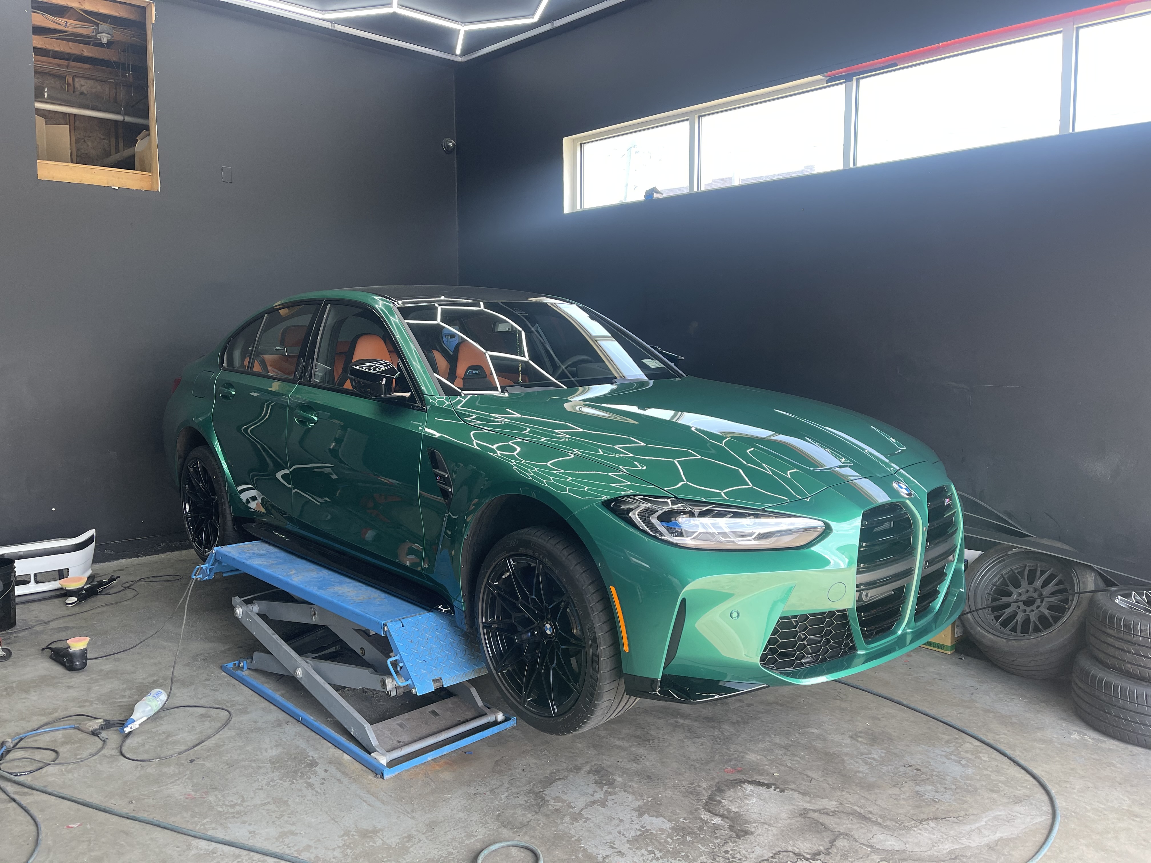 Green BMW M3 on lift in detailing bay